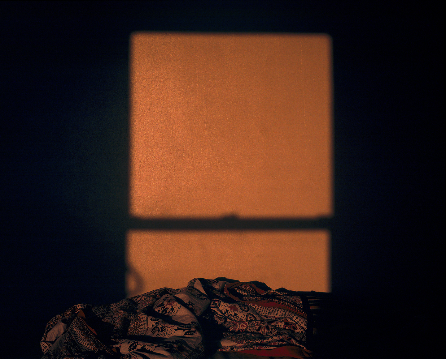 Orange Light Reflected on Wall from Window over a Bed